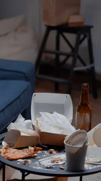 Resztki pizzy, puste butelki po piwie i serwetki na nieszczęsnym stole i podłodze — Zdjęcie stockowe