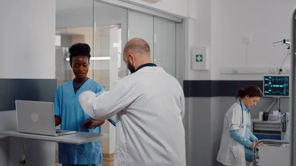 Νοσηλεύτρια ιατρών με ιατρική στολή δακτυλογραφώντας ανάκτηση θεραπείας σε φορητό υπολογιστή — Φωτογραφία Αρχείου