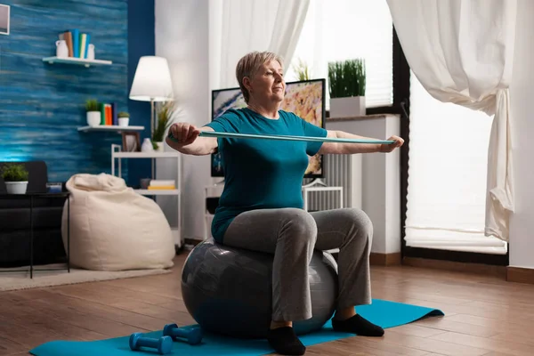 Focused senior woman stretching arm working at body muscle using fitness dumbbells — Stock Photo, Image