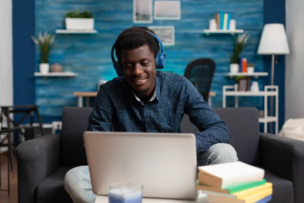 Estudante afro usando fones de ouvido ouvindo música enquanto digita ideias de marketing — Fotografia de Stock