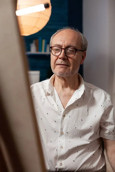 Portrait of senior artist looking at canvas with masterpiece — Stock Photo, Image