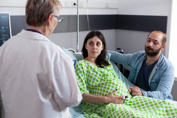 Porodnický lékař mluvit s párem s těhotenstvím — Stock fotografie