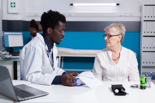 Homme noir avec profession de médecin parlant à un patient âgé — Photo