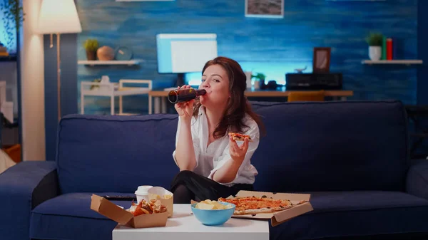 Person isst Pizza auf Couch und blickt in Kamera — Stockfoto