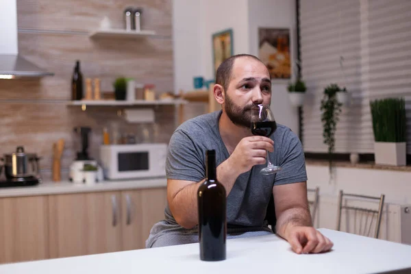 Кавказький чоловік тримає на кухні келих вина. — стокове фото