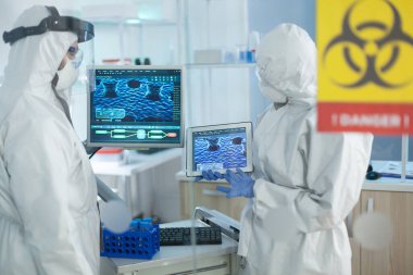 Koruyucu kıyafet giyen bilim adamlarından oluşan tıbbi ekip çalışması virüs gelişimini analiz ediyor.