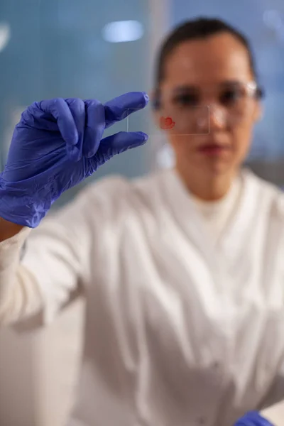 Trabajador de laboratorio analizando la muestra de sangre en vidrio — Foto de Stock