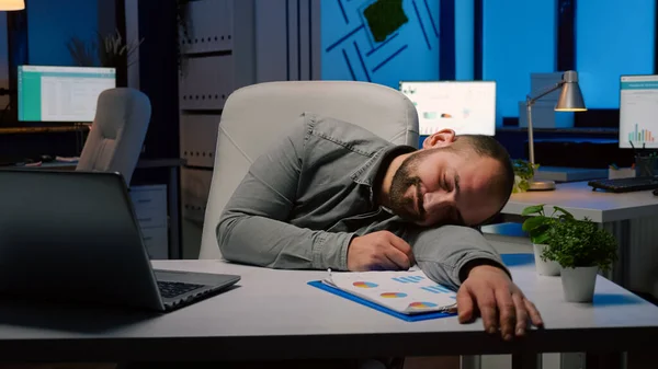 Utmattad överarbetad affärsman sover på skrivbord i start kontor — Stockfoto