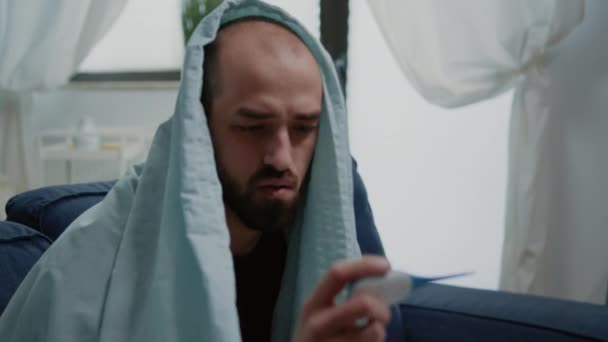 熱を測定する温度計を見て病気の男の閉じる — ストック動画