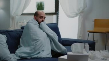 Soğuk algınlığı geçiren ve battaniyeye sarılmış titreyen biri.