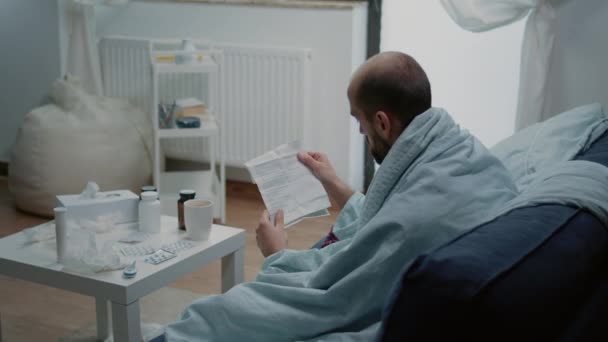 Взрослый человек с мигренью читает бумагу с информацией — стоковое видео