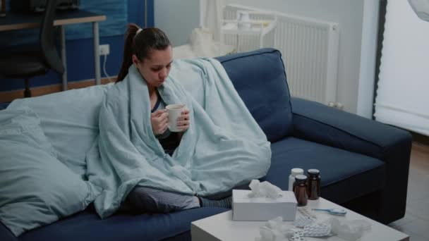 Zieke vrouw met kopje thee en zitten in deken — Stockvideo