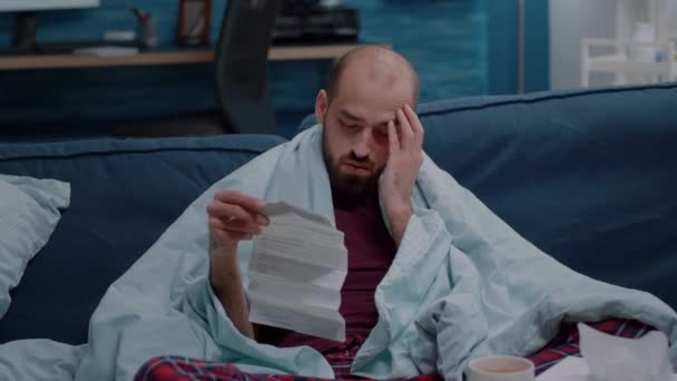 Niedobrze człowiek z bólem głowy patrząc na ulotkę medyczną — Wideo stockowe