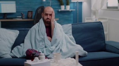Baş ağrısı ve grip belirtileri olan hasta bir adam kameraya bakıyor.