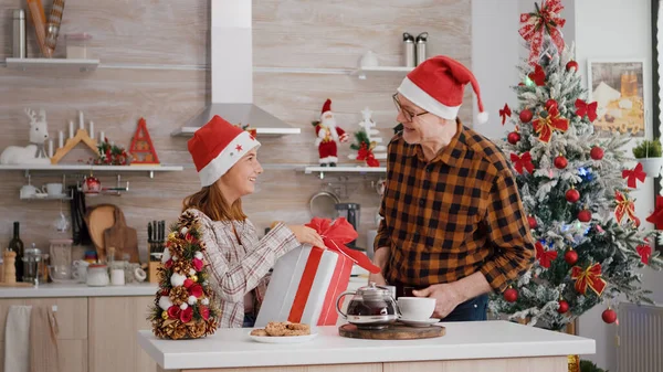 Großvater überrascht Enkelin mit Geschenkpapier in weihnachtlich dekorierter Küche — Stockfoto