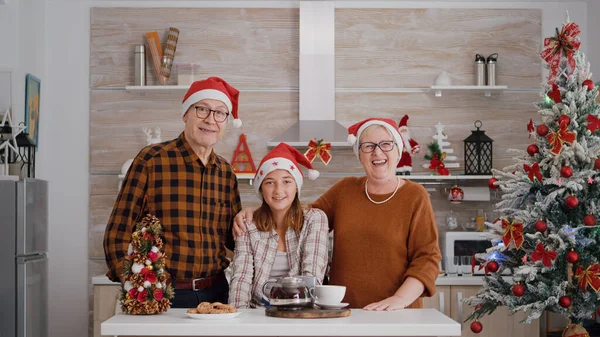 オンラインビデオ会議中にサンタの帽子挨拶リモート友人を身に着けている幸せな家族のpov — ストック写真