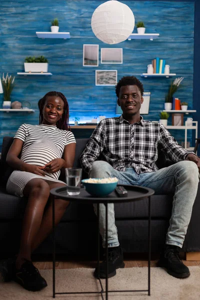 Hamileliği olan Afrikalı Amerikalı çift televizyon izliyor. — Stok fotoğraf