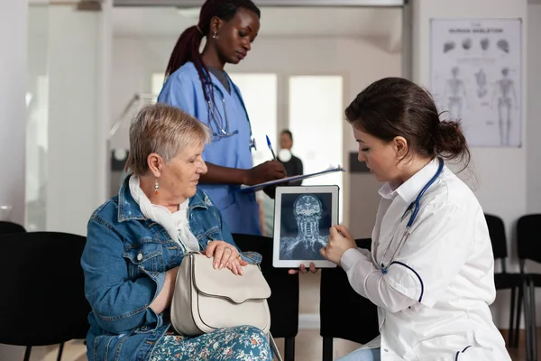Лікар-радіолог, який аналізує медичну рентгенографію з літньою хворою жінкою — стокове фото