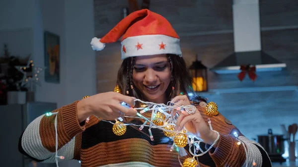 Mulher Festiva Com Chapéu Papai Noel Tentando Desembaraçar Luzes Enquanto — Fotografia de Stock