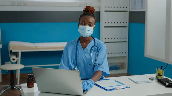Portret van een verpleegster die aan het bureau zit en laptop gebruikt — Stockfoto