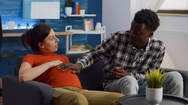 Jovem casal interracial com gravidez conversando sobre o bebê — Fotografia de Stock
