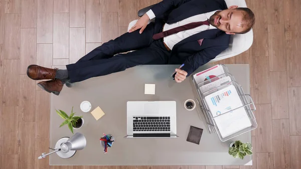 机の上に彼の足で立ってスーツで成功したビジネスマンのトップビュー — ストック写真