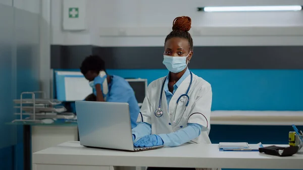 Portrait de jeune médecin utilisant la technologie de l'ordinateur portable sur le bureau — Photo