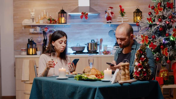 Casal moderno usando smartphones desfrutando de jantar festivo — Fotografia de Stock