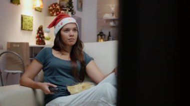 Noel Baba şapkası takan ve TV 'de film izleyen bir kadın.