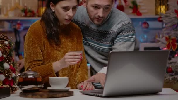 クリスマスショッピングをオンラインでクレジットカードで行うお祭りのカップル — ストック動画
