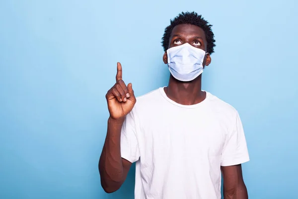 Обычный человек в маске против коронавируса, показывающий пальцем вверх. — стоковое фото