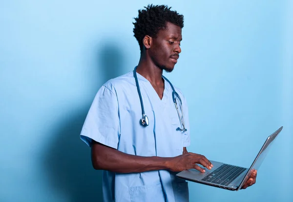 Assistente médico afro-americano olhando para laptop na mão — Fotografia de Stock