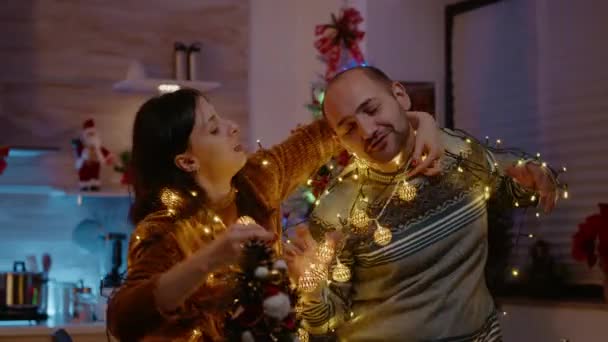 Festive couple knotted in string of christmas lights — Stock Video