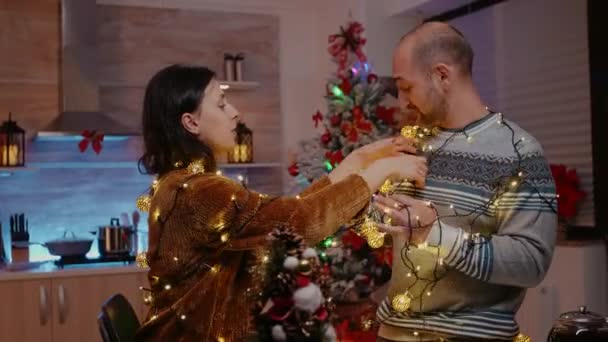 Festive couple trying to untangle garland of twinkle lights — Stock Video