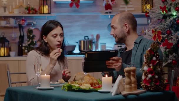 Pár těší vánoční večeři a při pohledu na tablet — Stock video