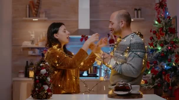 陽気なカップル取得巻き込まガーランドのクリスマスライト — ストック動画