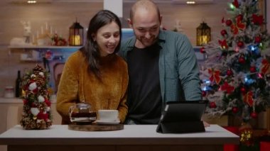 Noel arifesinde online video araması için tablet kullanan çift