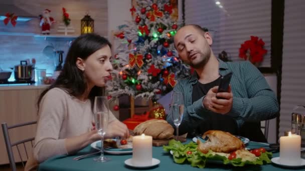 Mann und Frau beim Festessen mit Blick aufs Smartphone — Stockvideo