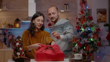 Noel hediyesi olarak kırmızı kağıt paketleyen erkek ve kadın.