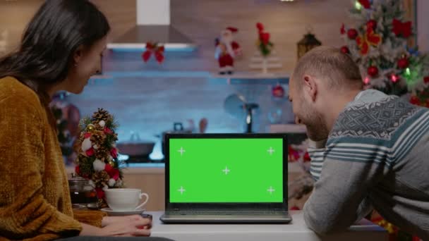 Праздничная пара смотрит на горизонтальный зеленый экран на ноутбуке — стоковое видео