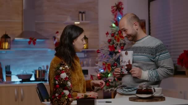 Festliches Paar signiert Weihnachtskarte für das Weihnachtsfest — Stockvideo