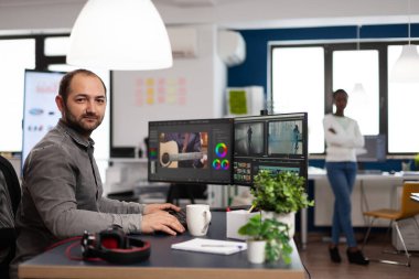 Yaratıcı videocu adam kameraya bakıp gülümsüyor.