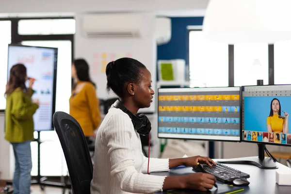 Zwarte retoucher kunstenaar analyseren van beelden op pc met twee monitoren — Stockfoto