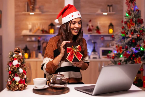 Caucasian woman opening present on video call — Stock Photo, Image