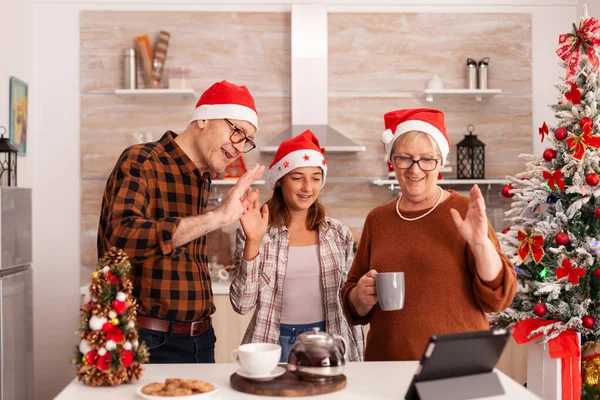 Glückliche Familie mit Weihnachtsmütze grüßt entfernte Eltern, die Weihnachten feiern — Stockfoto