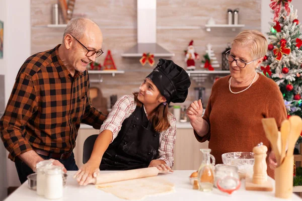 Lächelnde Familie steht in weihnachtlich dekorierter Küche am Tisch und feiert Weihnachten — Stockfoto