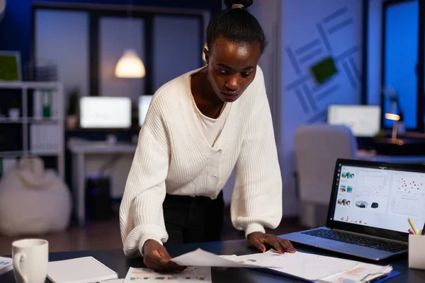 Concentrato sovraccarico di lavoro afroamericano donna d'affari analizzando grafici di profitto documenti finanziari — Foto Stock