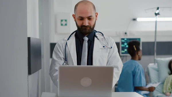 Front view of practitioner doctor typing illness expertise on computer — Stock Photo, Image