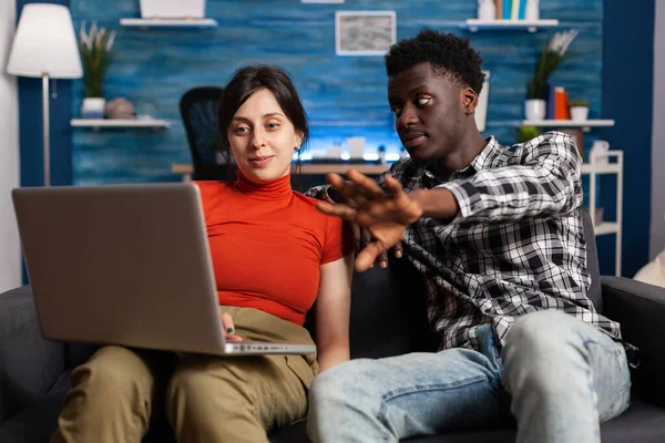 Modern dizüstü bilgisayara bakan evli, ırklar arası bir çift.