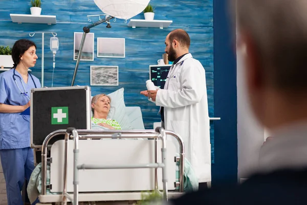 Doctor hombre discutiendo tratamiento medicamentoso con jubilada anciana enferma —  Fotos de Stock